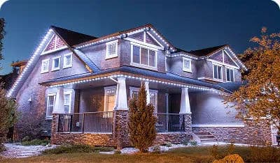 Modern home adorned with festive outdoor lights at twilight, highlighting architectural details.