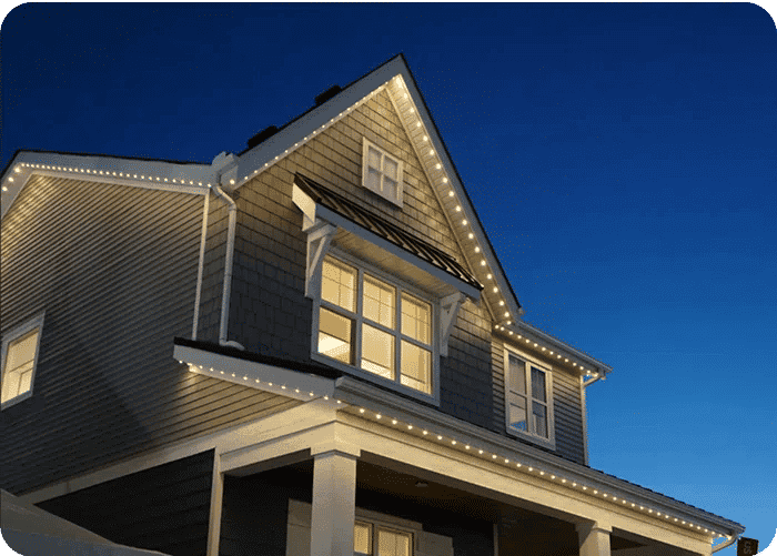 Modern house exterior at twilight with warm LED lights outlining the roofline.