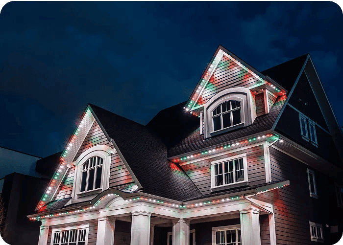 Festively lit house at night with vibrant red and green holiday lights.