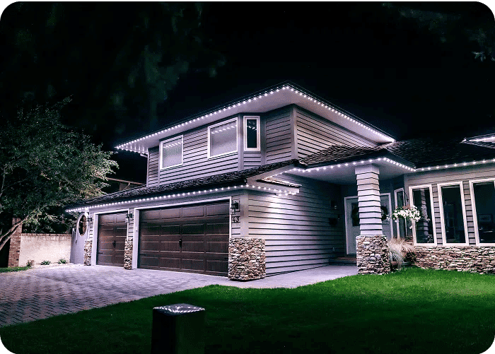 Modern home at night adorned with LED lights and landscaped yard.