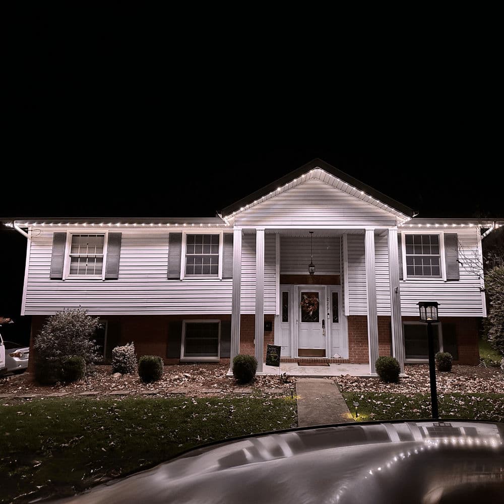 Front view of a illuminated home decorated with Christmas lights at night.