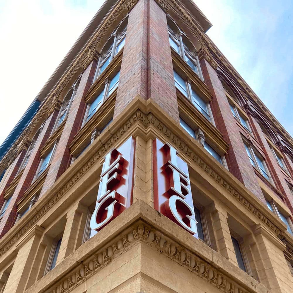 Historic brick building corner with bold red IFC signage against a clear blue sky.