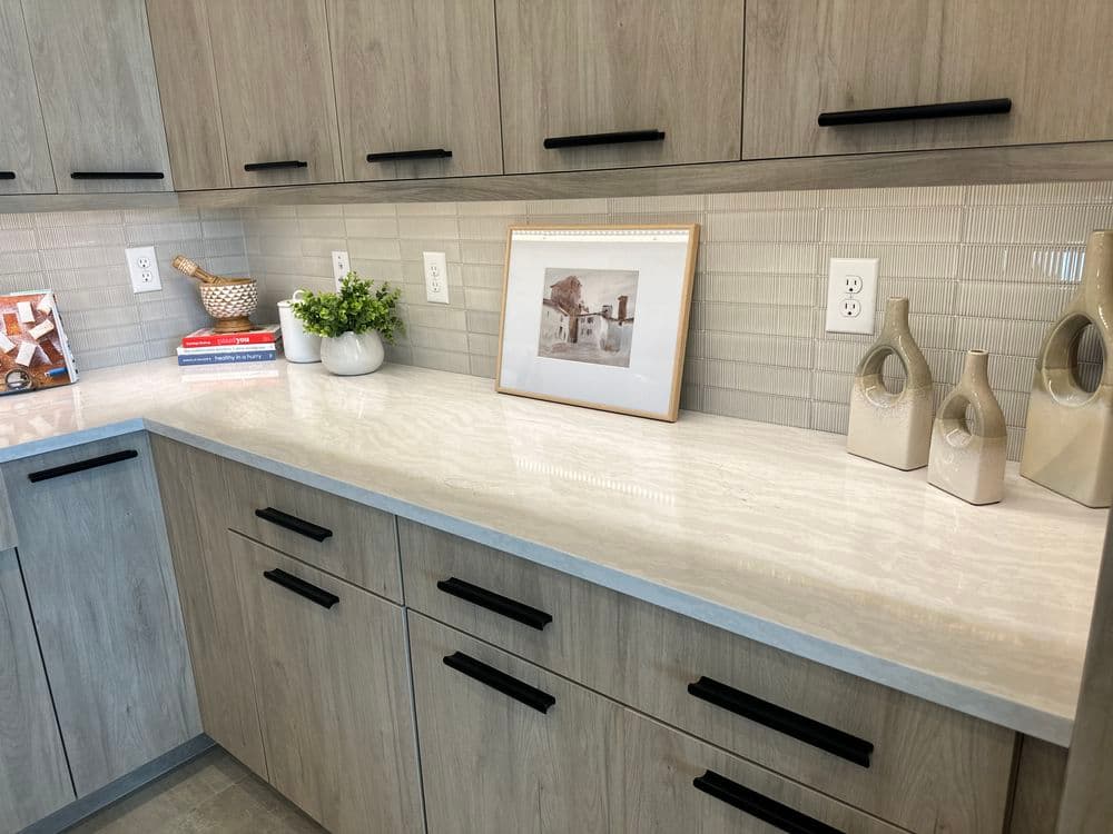Modern kitchen countertop with wooden cabinets, decorative vases, and an art frame.
