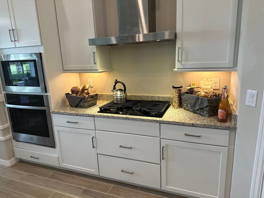 Modern kitchen with granite countertop, stainless steel appliances, and decorative storage baskets.