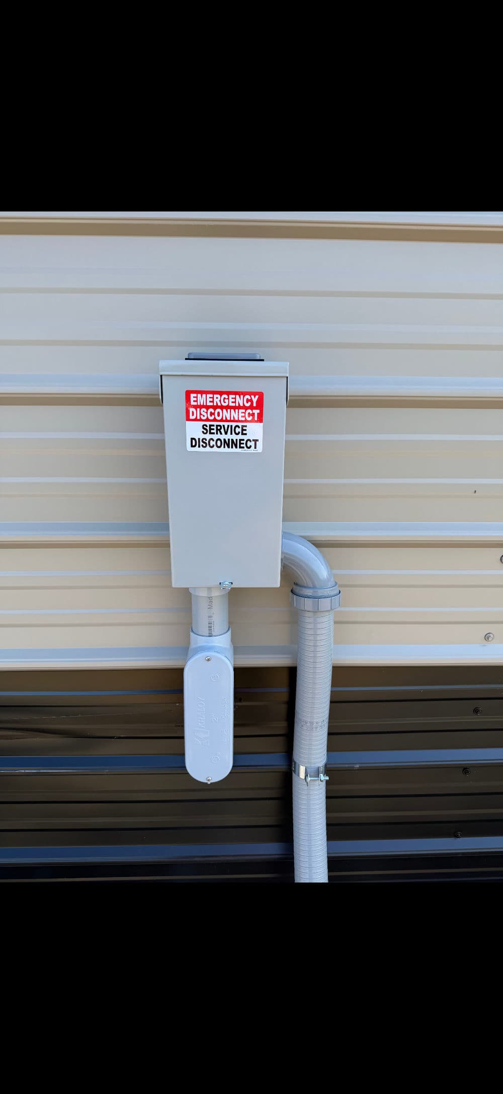 Emergency service disconnect box mounted on a wall with clear labeling and conduit.