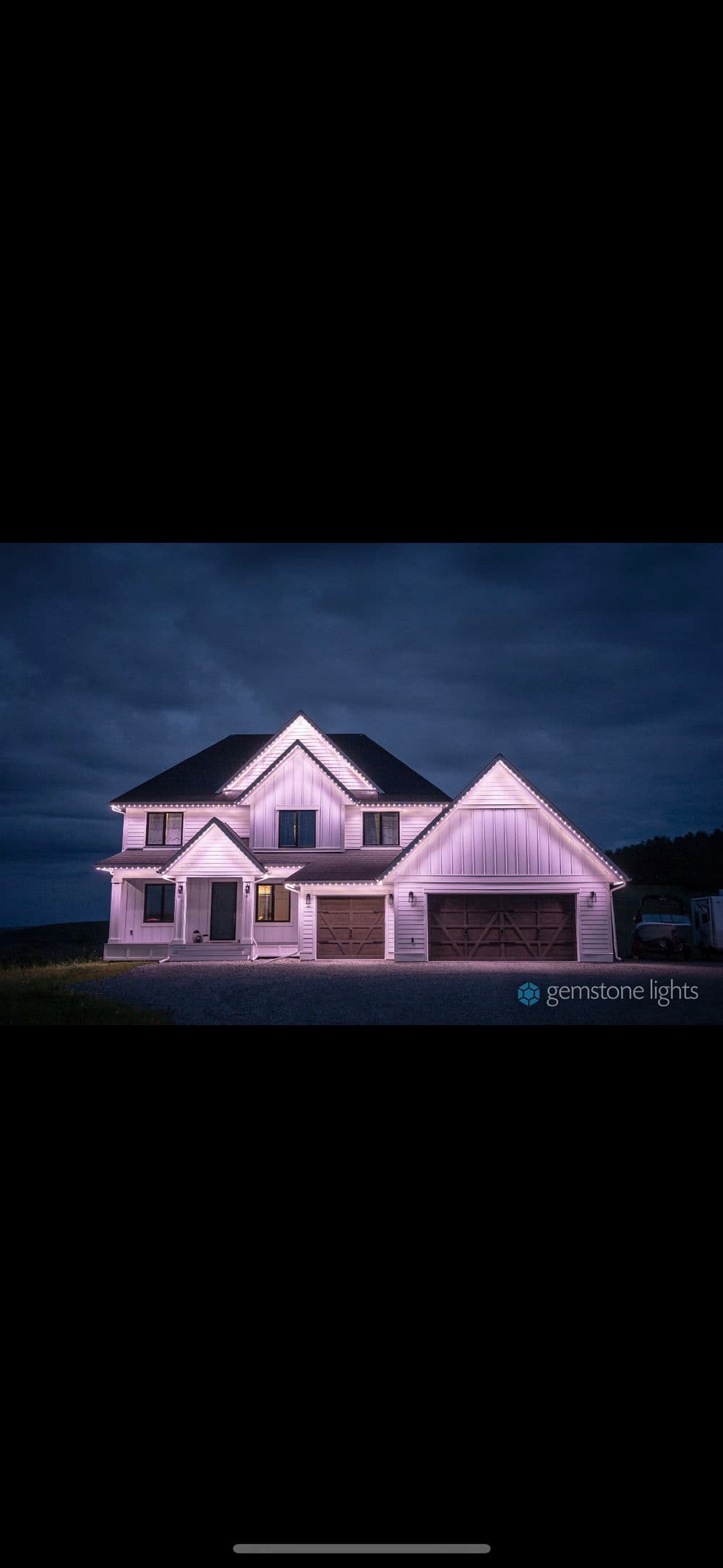 Modern home illuminated with Gemstone Lights under a cloudy evening sky.