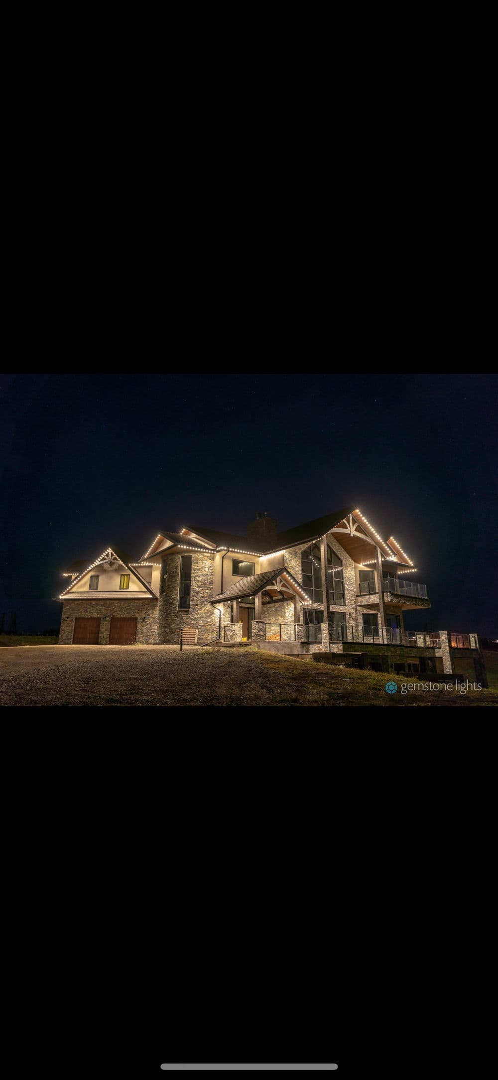 Elegant mountain house with stone exterior and illuminated details, set against a night sky.