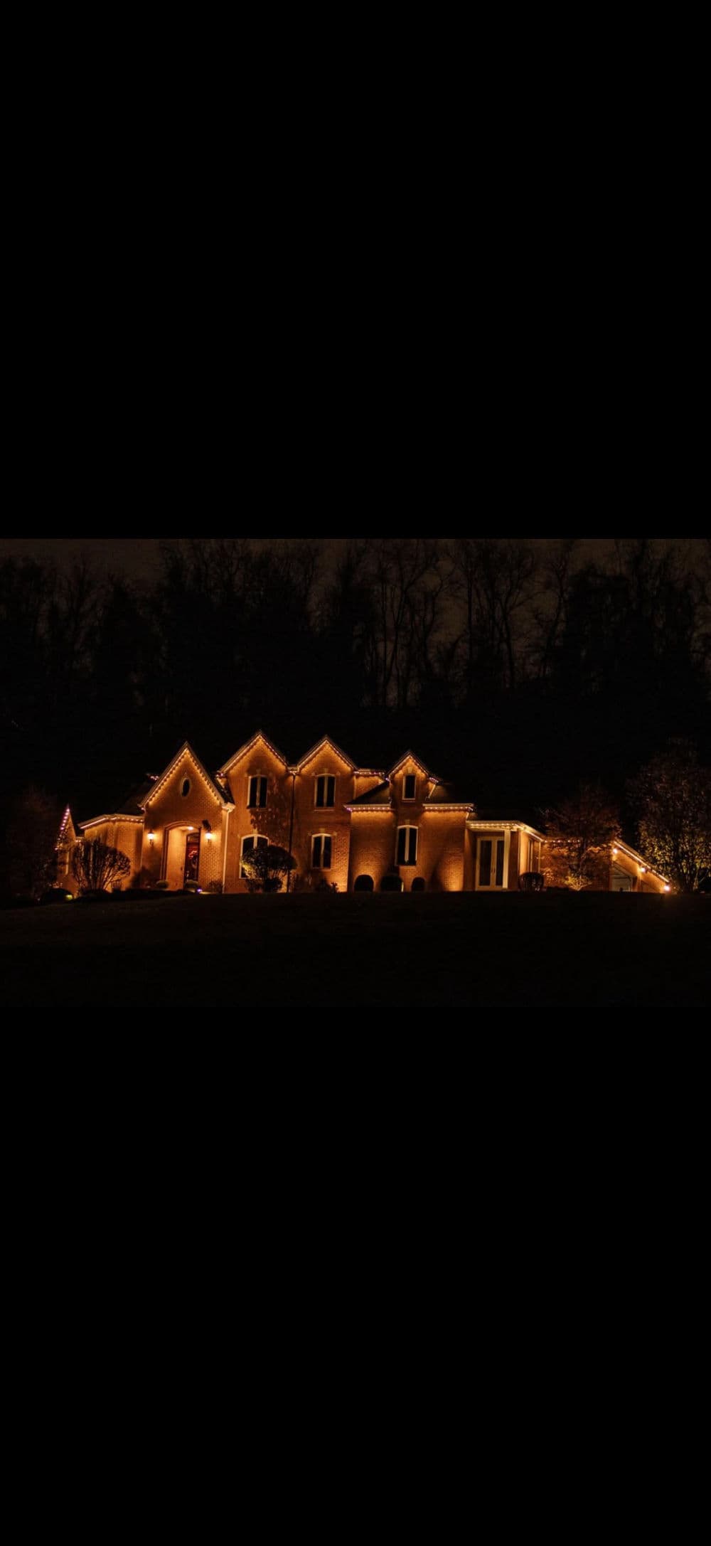 Elegant house illuminated with festive lights at night, showcasing modern architecture and holiday spirit.