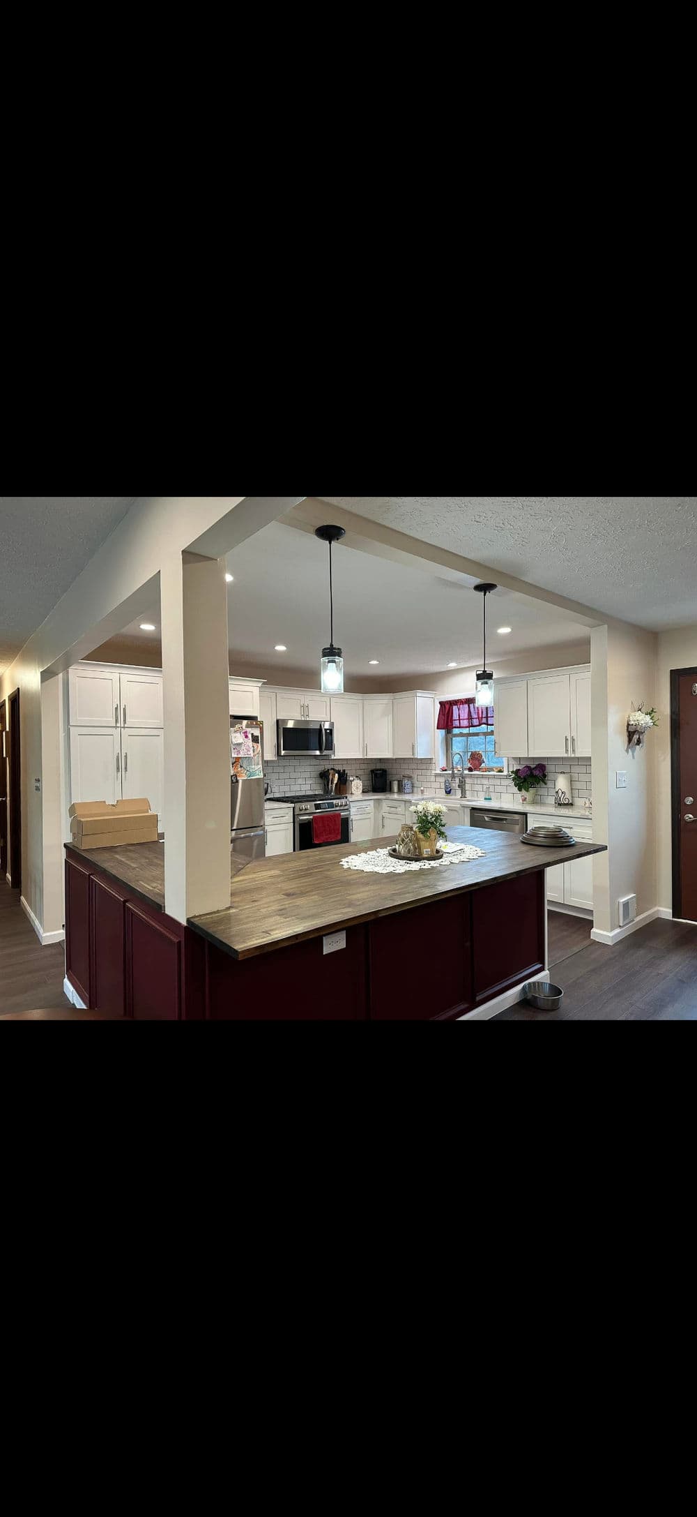Modern kitchen featuring a large island, pendant lights, and white cabinetry.