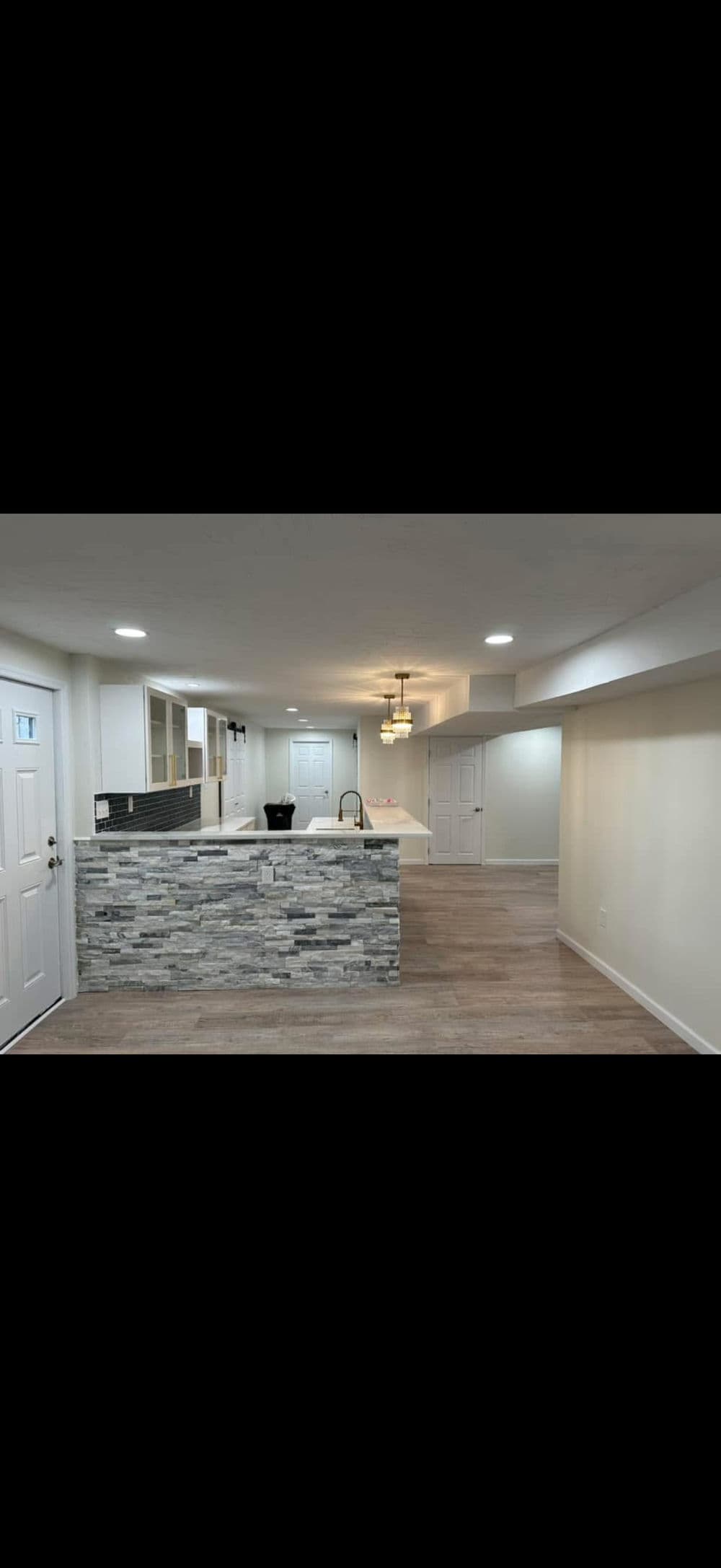 Modern open-concept living space featuring stone-accented kitchen island and bright lighting.