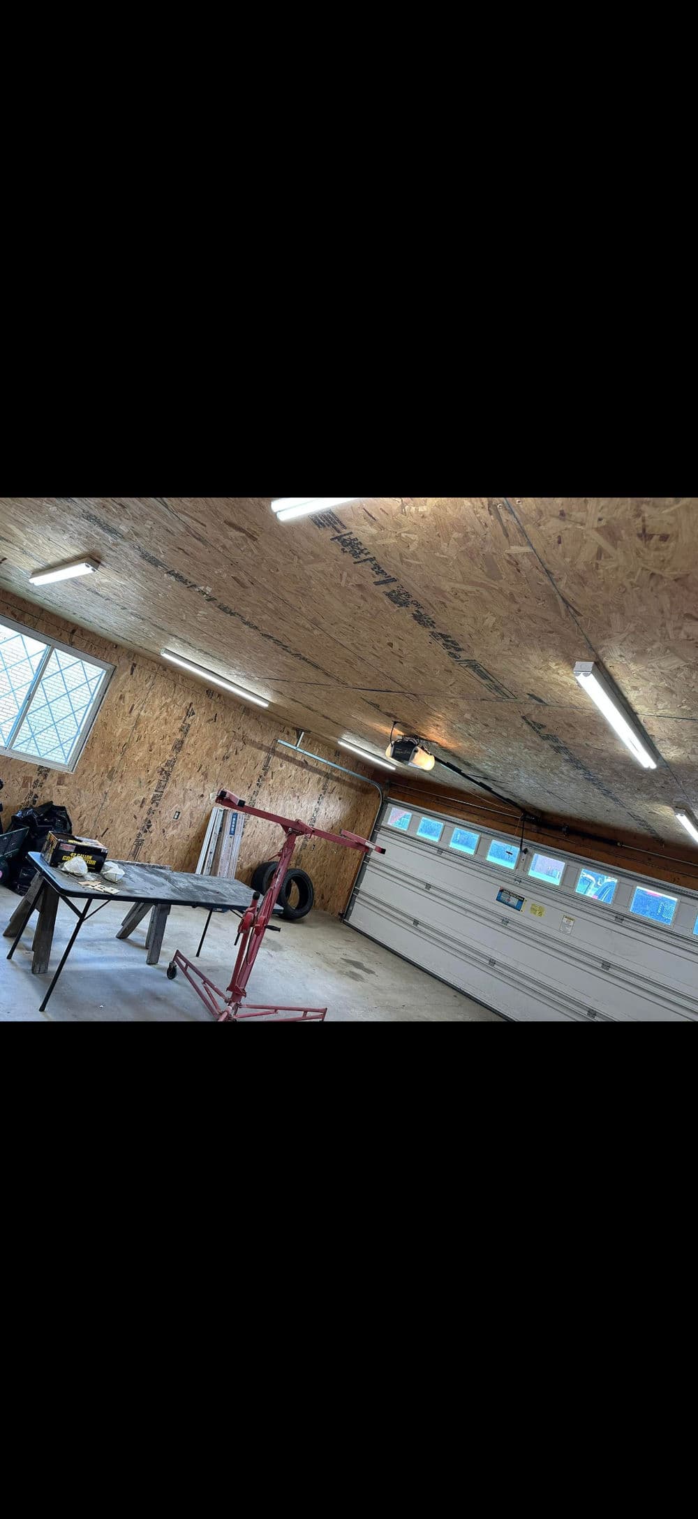 Bright garage interior with workbench, tire, and overhead lighting. Spacious and well-maintained.
