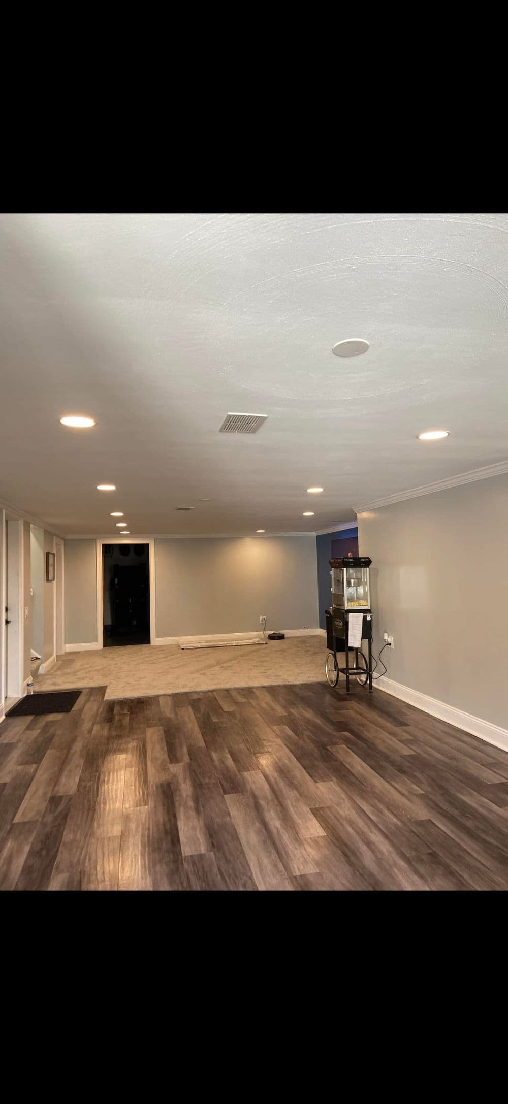 Spacious, modern basement with light hardwood flooring and popcorn machine. Ideal for entertainment.